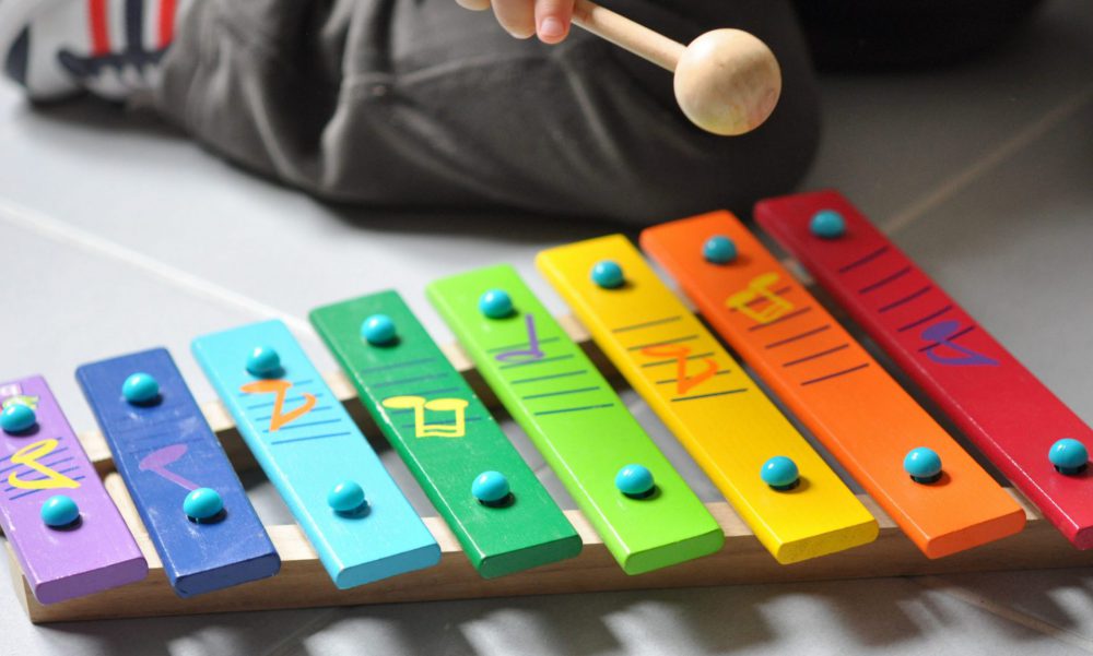Child playing coloured xylophone.